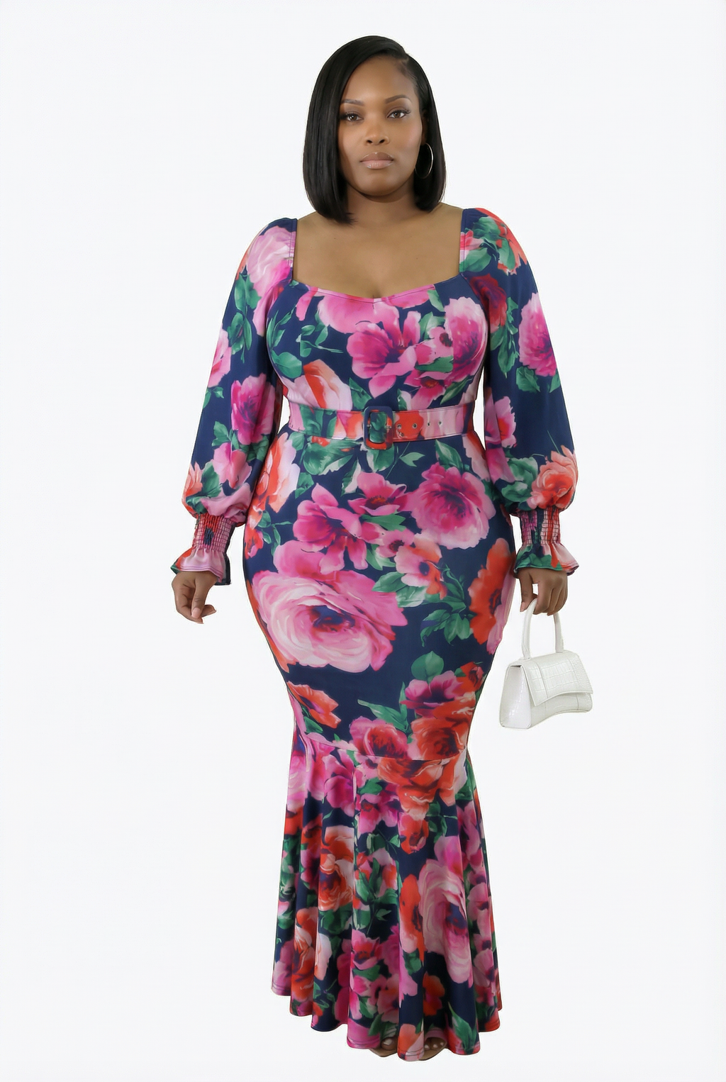 Woman wearing a floral dress holding a white handbag on a white background